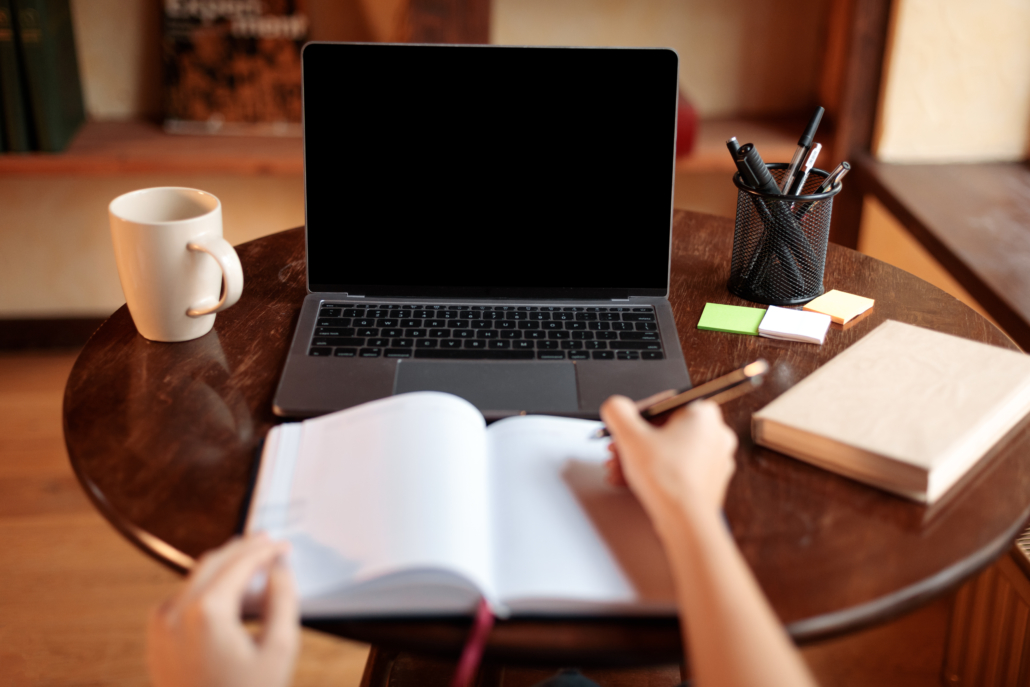 Woman sitting at desk using laptop with blank screen, mockup